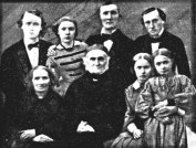Familjeporträtt - Elias och Christina Fries och sex av deras barn. Fotografi taget sannolikt år 1859 i ett av växthusen i Uppsala botaniska trädgård.